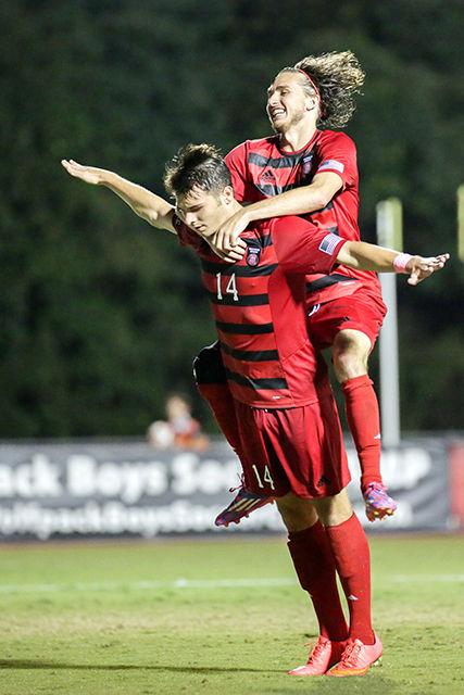 Teammate Yanni Hachem jumps on the back of Junior defense Reed Norton in celebration after Norton's scored a second goal in the 76th minute of play against Louisville this past Friday, October 3rd, 2014. The Wolpack took the win against Louisville 2-1 in Dail Soccer Stadium in front of 681 fans and a pep band. Photo by Nick Faulkner