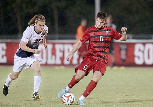 Sophomore midfielder Michael Bajza chips the ball over the goalkeeper for the second goal in the Wolfpack&#8217;s 4-1 win against Liberty at the Dail Soccer Stadium Tuesday.