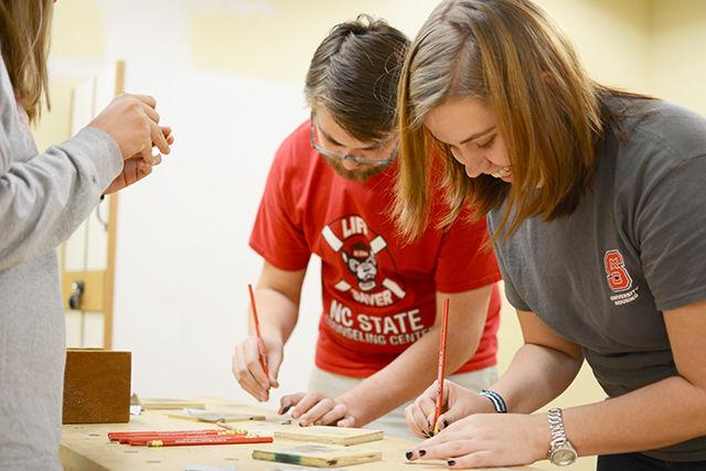 While laughing, junior in social work Erin Tooley makes her lens for her pinhole camera. The Craft Center held its annual Pinhole competition after having students build them Sept. 19.