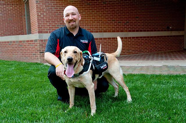 David Roberts, assistant professor of computer science, poses with a dog wearing the harness designed to enhance communication between dogs and humans. The new developments could create more effective training for service dogs and provide information about dogs' emotional responses to different situations.