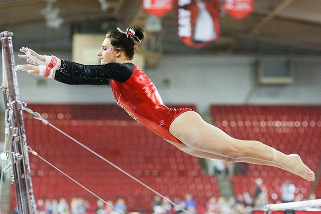 Junior Michaela Woodford launches herself onto the uneven bars during the gymnastics meet on Saturday against West Virginia University, William &amp; Mary and UNC-Chapel Hill. Woodford pulled a 9.700 during her routine and took first place in the all-around. The Wolfpack placed third in the meet with a score of 194.050.