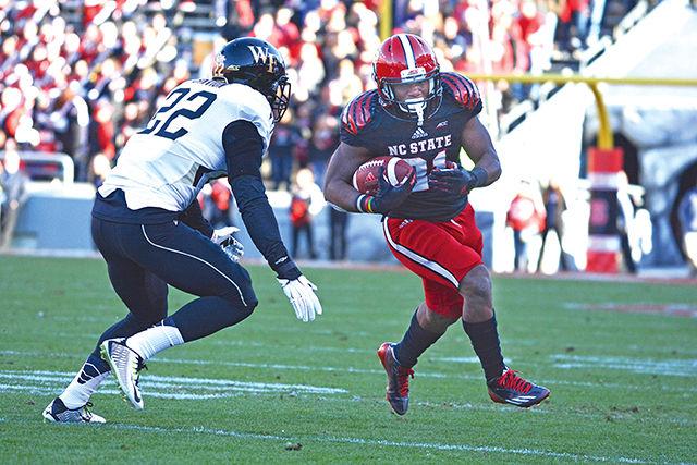 Then-sophomore running back Matt Dayes dodges an opposing player as he runs the ball downfield against Wake Forest. The Wolfpack beat the Demon Deacons 42-13 at Carter Finley Stadium Nov. 15, 2014.