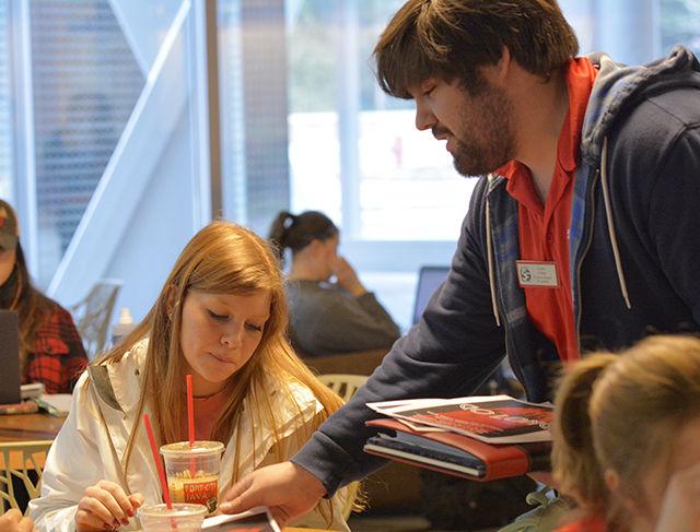 Cody Long, a junior studying history and the incumbent candidate for Student Senate President, hands out a flyer to Jordan Feuerhelm, a sophomore studying business administration, encouraging her to vote for him in the upcoming Student Government elections at the One Earth food court in the Talley Student Union Monday. When asked about how he felt about the campaign schedule being shortened from two weeks to one, Long said there is less stress put on him as a student, but more stress put on him as a candidate.