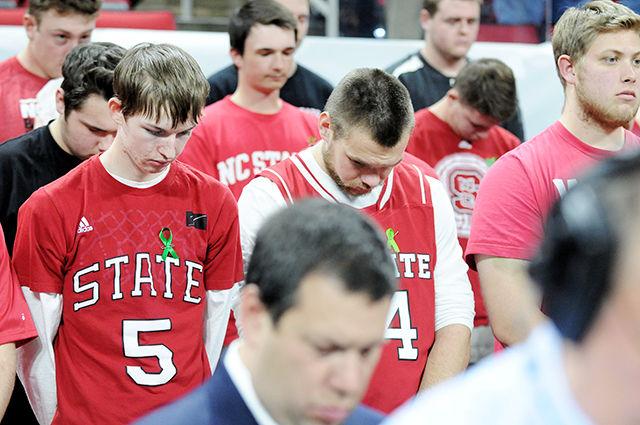 Fans pause for a moment of silence at the men's basketball game against Virginia Wednesday at PNC Arena.