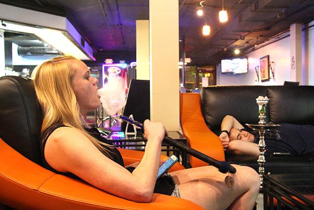 Courtney Weaver, junior in business administration at Wake Technical Community College, takes a puff of Hookah at the new bar Fuzion Cafe Lounge while Zack Khoueori, who works in Raleigh, rests while watching a soccer match on one of the couches. The new bar, recently opened on Hillsborough street, gives the ambience of a hookah bar as well as a coffee shop.
