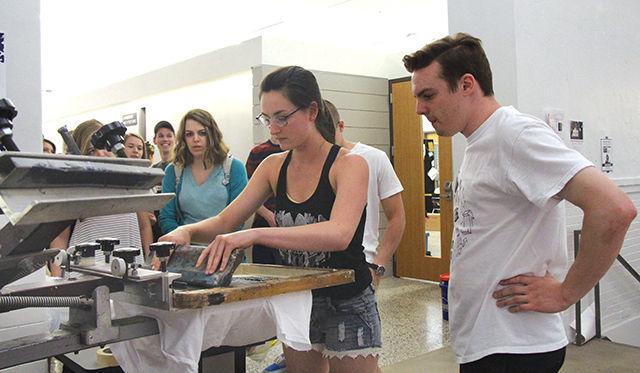 Brett Morris, 2013 College of Design graduate, teaches Sarah Hardison, a sophomore studying graphic design, how to screen print T-shirts at the Studio Collective 2015 at Leazar Hall on Saturday. "I love screen printing. Teaching people how to print fires me up more than anything else," Morris said. This is the second Studio Collective hosted by College of Design. "It is an initiative to showcase all the work we do in an entire year. We want the students to come and see our work and appreciate it as we give back to the community something valuable," said Ryan Williams, a freshman studying graphic design and one of the organizers of the event.