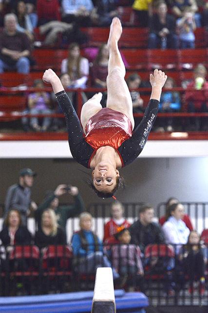 Junior Michaela Woodford flips head over heels on the balance beam Jan. 31, 2015 during NC State's quad-meet with William &amp; Mary, West Virginia, and UNC-Chapel Hill at Reynolds Coliseum. Woodford had a stellar performance, finishing second on the beam (9.850), tied for third in the floor exercise (9.825), and first all-around (39.175). The Wolfpack squad finished third overall behind West Virginia (195.350) and UNC-Chapel Hill (194.500) with a total score of 194.050.