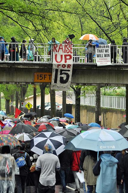 Protesters march under the footbridge on S. Blount St. bridge during the Fight for $15 rally held at Shaw University Wednesday evening. Rally participants protested for a higher minimum wage of $15 and union rights. Fast-food workers, child care providers, and educators were amongst those represented at the rally.