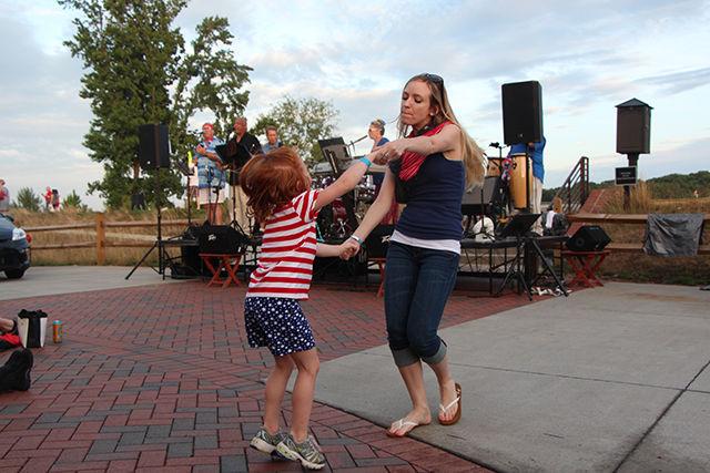Ellie Davis dances with her aunt Mandy Greene on the music played by local band Bailey's Comet at Lonnie Pool Golf Course at NC State. Many people gathered here to celebrate Fourth of July and watch the fireworks that takes place downtown from there.
