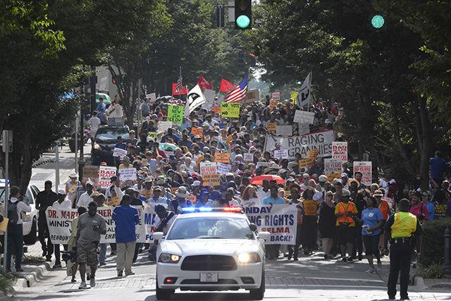 Activists march in support of voting rights in downtown Winston-Salem on Monday. Thousands were in attendance as a band sang traditional music, some of which were updated to fit the current situation while others recited poetry and called the crowd to action. After the initial speakers came to the stage, the mass in attendence marched past the local courthouse and returned to the stage to hear speeches from several community leaders, most notatbly Reverand Doctor William Barber. photo by Gavin Stone