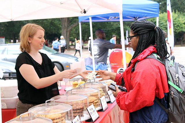 Lexi Bynum, a freshman studying political science, buys a cookie from a vendor at the NC State Farmers Market. The Farmers Market made its return to the brickyard on August 26th, where it will recur every Wednesday from 11:30 to 1:30. The event is run through a student organization and has been in existence for six years. "It was started to mix education with local production... [we] wanted to give local producers a viable market and then also connect the student body to producers," says Hannah Frank, co-market manager. Products sold at the market include Italian ice, jewelry, and baked goods.