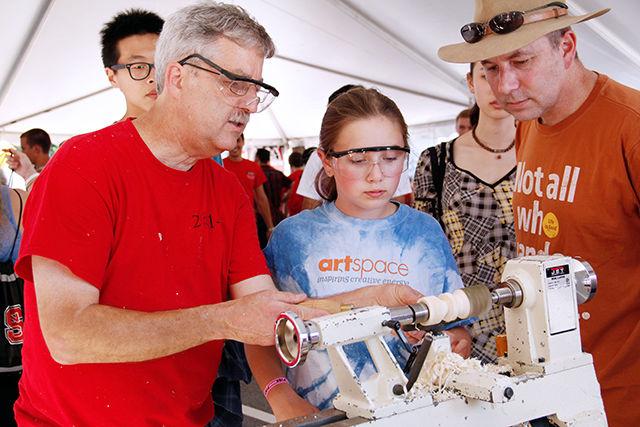 Zoe Watts from Ligon Watts school visits 2015 Packapalooza with her dad and learns how to use a wooden lathe from the Director of craft center, George Thomas on Saturday.