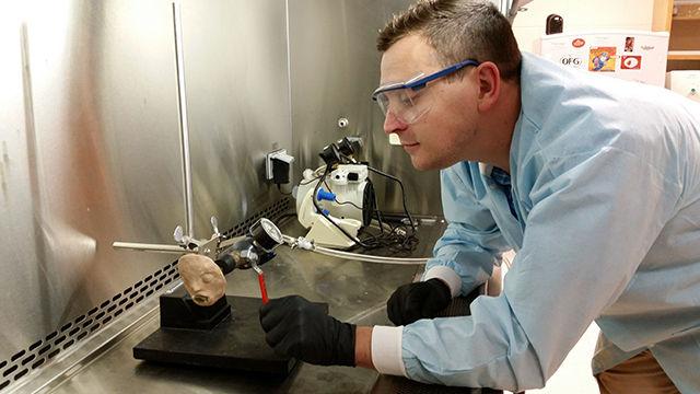 Dominic Libera demonstrates how the vomit machine works. The machine was designed to simulate human vomiting and determine how disease can be spread. The team worked to determine if viruses can be suspended in the air after the process of vomiting.