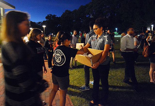 Kam Risku, a sophomore studying Psychology, hands out candles to people for the vigil of Joseph Alexander Banks. Risku, a student leader in NCSU's Union Activities Board, says, "I'm very saddened by the loss we have faced, but comforted by the unity of the Wolfpack."