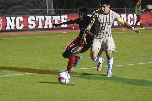 NC State Men's soccer red shirt senior midfielder Philip Carmon shields the ball and looks for a pass. NC State won against The College of Charleston with a final score of 2-0. The game took place on Monday, August 31st at Dail soccer stadium.