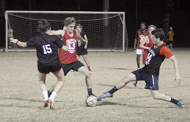 James Cumbo, a sophomore studying management, attempts to dribble between two defenders, Sarah Yoder, a junior studying biological sciences, and Jason McCormick, a freshman studying science, technology and society. His team, the 336 Mafia, lost the game 7-3 on Miller Field Tuesday.
