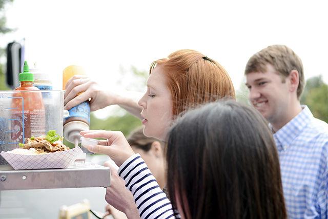 A customer pours hot and sweet sauce on her Cheerwine Bulgogi Sloppy Joe on the food truck. They were located at Trinity Place on Sept. 24, 2015 from 11:30 am to 1:30 pm.&#160;
