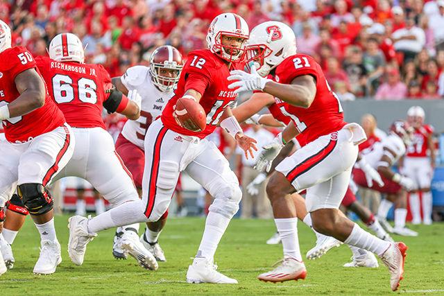 Redshirt Senior Jacoby Brissett hands the ball off to runningback Matt Dayes against the Troy Trojans on Saturday, September 5th, 2015. Brissett had an outstanding performance by completing 21 of 23 passes for 196 yards and two touchdowns. The Wolfpack defeated the Trojans 49-21 in their first game of the season.