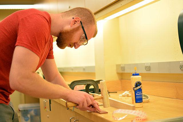 Matt Hooper, a junior studying Environmental Technology and Management, constructs a cigar box guitar in a class that is held at the Crafts Center of NC State. Hooper says that he knows how to play acoustic guitar. He also mentioned that he built one in high school, since he took cabinet making in high school for two years.