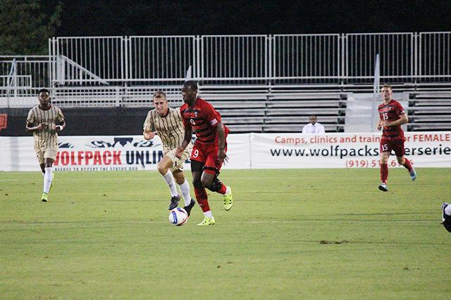 Sophomore forward Ade Taiwo runs the ball, keeping it away from College of Charleston's Lorenz Esposito at Dail Soccer Stadium Monday, August 31st. The Wolfpack defeated the Cougars 2-0, with one goal by freshman forward Julius Duchscherer, and another by junior midfielder Yanni Hachem.