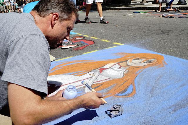 Jeff Miller paints in a square on Fayetteville Street on 9/19. This is his family's 4th year coming to SPARKcon. Street painting is a major part of SPARKcon's art section, where schools, organizations, and families can buy squares on the street to paint on.