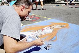 Jeff Miller paints in a square on Fayetteville Street on 9/19. This is his family's 4th year coming to SPARKcon. Street painting is a major part of SPARKcon's art section, where schools, organizations, and families can buy squares on the street to paint on.