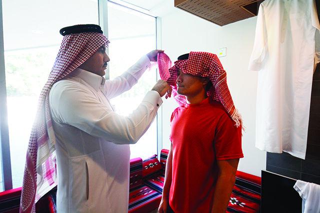 Wajih Abuzid, a member of the Saudi Student Organization, helping Bobby Willis, a senior studying electrical engineering, try on a shemagh, a tradional headscarf worn by men, at the Cultural Showcase on Thursday in the One Earth Lounge of the Talley Student Union.&#160;