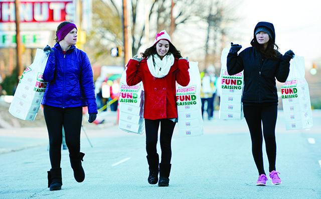 (From left) Darby Leinbach, a freshman studying political science, Victoria Beever, a freshman studying communication, and Deanna Davidson, a sophomore studying applied nutrition, carry boxes of Krispy Kreme doughnuts to the race route prior to the start of the Krispy Kreme Challenge Feb. 14, 2015. The 11th annual race attracted thousands of runners hoping to conquer the challenge of running five miles with a dozen-doughnut pit stop at the halfway point in less than 60 minutes.