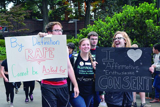 Jackson Buck, a junior studying creative writing, Alicia Criswell, a freshman in exploratory studies, and Carolina Gabriel, a junior studying communication, participate in the SlutWalk on Thursday. Participants handcrafted signs with affirmative messages to carry while on the walk in an aim to end victim blaming in rape cases.