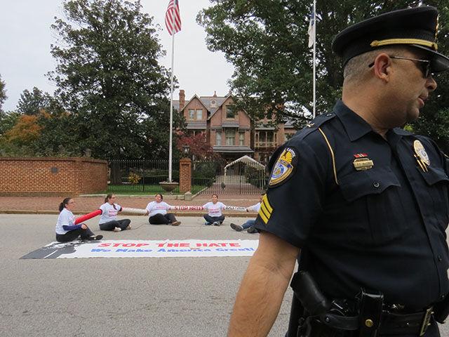 A police officer tries to keep the crowd or protesters off the street in front of the Governor&#8217;s Mansion.