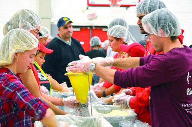 Funnel stations are manned by 5 people, each one with a specific job. In this stage, a sauce packet, soy wheat protein, vegetables, and rice are added with enough of each to serve a total of 6 people when cooked. Bags were made for Stop Hunger Now as a part of Service NC State on Friday, November 13, 2015.