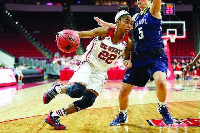Redshirt Junior guard Dominique Wilson dribbles around a Wildcat defender towards the baseline against the Villanova Wildcats. Wilson finished with 21 points, 6 rebounds, and 3 assists in 35 minutes of gameplay. The NC State woman's baskeball team won against Villanova 70-64 in the season opener to go to 1-0 on the season on November 13, 2015 at PNC Arena.