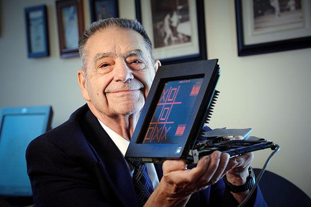 Donald Bitzer holds a model of his PLATO touch screen. The touch screen featured a monochromatic display only showing orange that could be programmed to display custom graphics.&#160;
