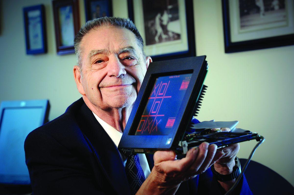 Donald Bitzer holds a model of his PLATO touch screen. The touch screen featured a monochromatic display only showing orange that could be programmed to display custom graphics.&#160;