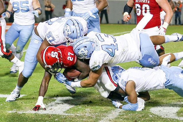 Redshirt sophomore runningback Dawka Nichols gets swarmed by UNC defenders in the second half of the football game. Nichols had four carries for 10 yards and 1 catch for 4 yards. The NC State Wolfpack fell to the UNC Tarheels, in the last home game of the season, 45-34 at Carter-Finley Stadium on November 28, 2015.