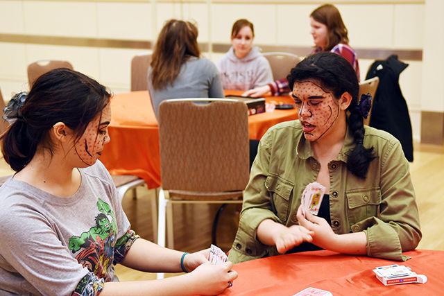 Akira Romero, a sophomore studying biomedical engineering, explains the rules of the card game War to Chyna Lim, a sophomore studying mechanical engineering, at PackCon on Tuesday in the Coastal Ballroom in Talley.