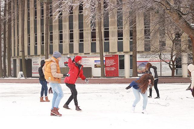 Undergraduate students have a snow ball fight on the Brickyard on Saturday.
