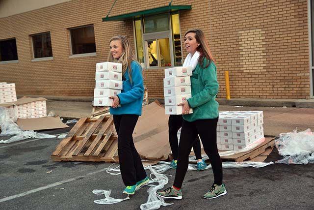 Whitney Ford, a sophomore studying business administration, and Laura White, a sophomore sudying management, carries doughnuts to set up for the Krispy Kreme Challenge outside the Krispy Kreme on N. Persons St., Saturday, Feb 6th, 2016.