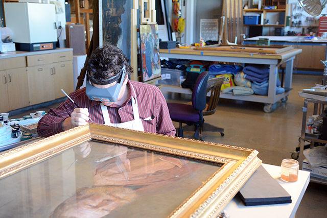 Perry Hurt, an associate conservator at the North Carolina Museum of Art, works to touch up the frame of a painting in the conservation lab of the museum Friday. This painting, "Sea Dog," done by Andrew Newell Wyeth in 1971, was given to the museum by R.J. Reynolds Industries, Inc. Hurt, along with other conservators, will be restoring paintings where the public can observe the work in an exhibit called "Actual State,&#8221; which runs until July 10.