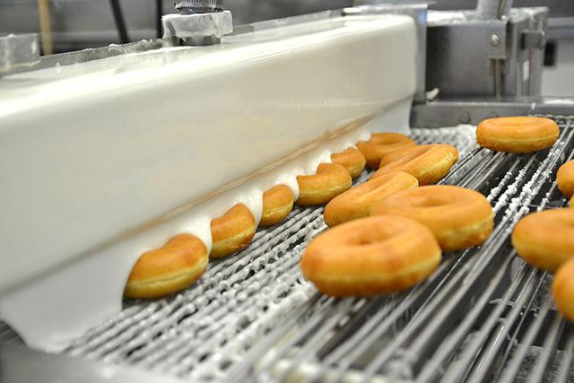 In rows of six, the doughnuts go under the icing machine to be made into the original glazed doughnuts. Participants of the Krispy Kreme Challenge will eat a dozen original glazed doughnuts at the halfway point at the Krispy Kreme in downtown Raleigh.