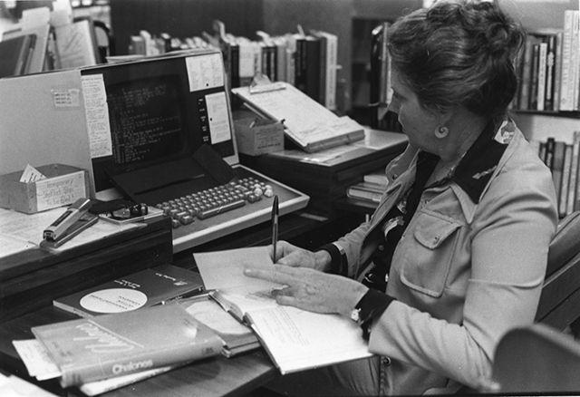 Circa 1980-1989. A reference librarian works on a computer.