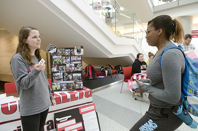 Elizabeth Carter, a junior studying microbiology, hands Riki Dows, a freshman studying communication media, a service raleigh sticker on Feb 16, 2016 in Talley Student Union. Service raleigh is an organization that partners groups and individuals with other non profit organizations for Raleigh's day of service. "I'm in girl scouts at home and I have been missing service projects since I came to Raleigh."