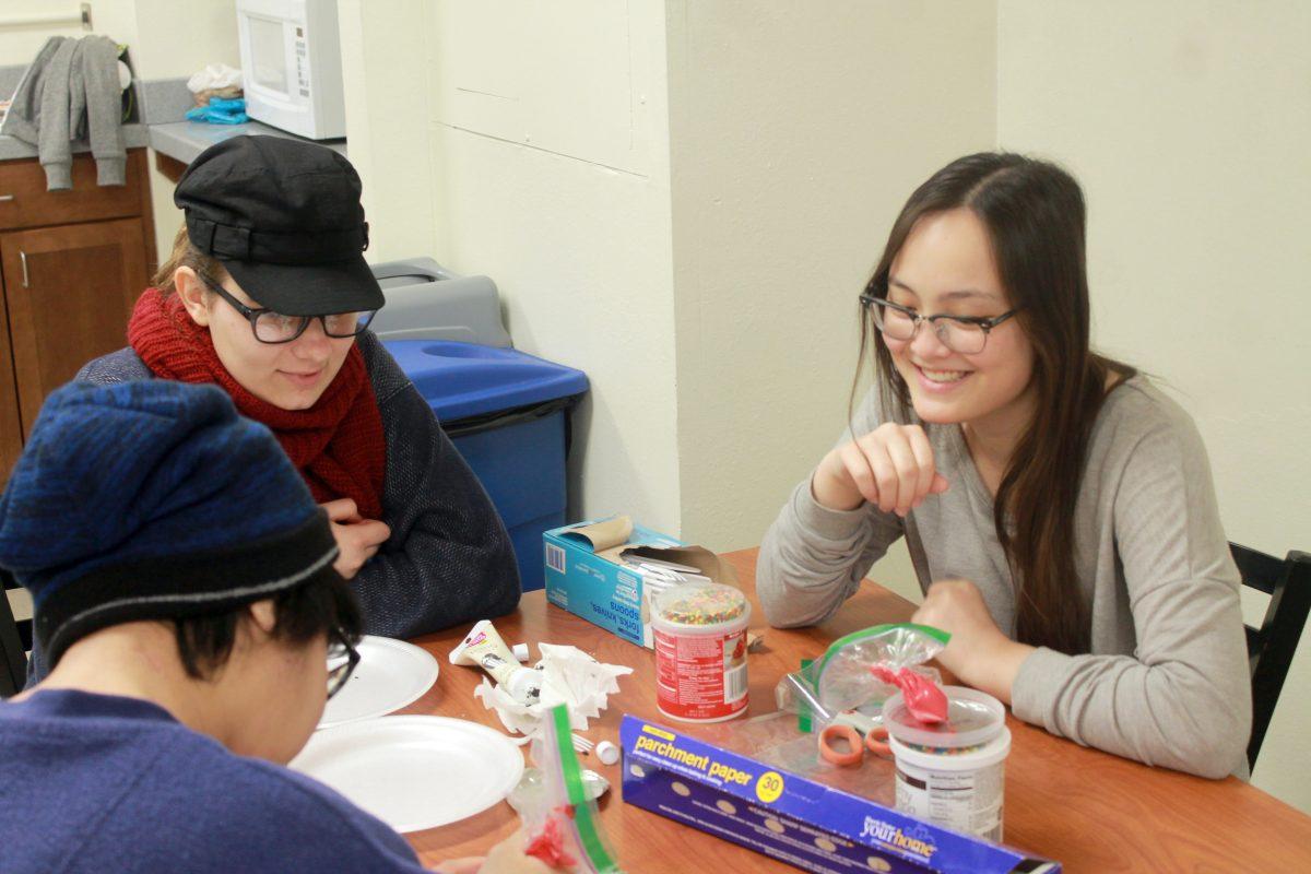 Jo Himes, Zoe Shirk and Sarah Wong, members of the new organization, Adopted Students Union, decorate cookies with the symbol for adoption to hand out in Talley Student Union.&#160;