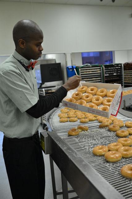 Andre Milton, the Assistant General Manager, picks a dozen Krispy Kreme doughnuts for a customer straight off of the prodction line on Wednesday, Feb. 3, 2016. These doughnuts have been freshly made for less than a minute or two by the time the customer has them in his or her hands.