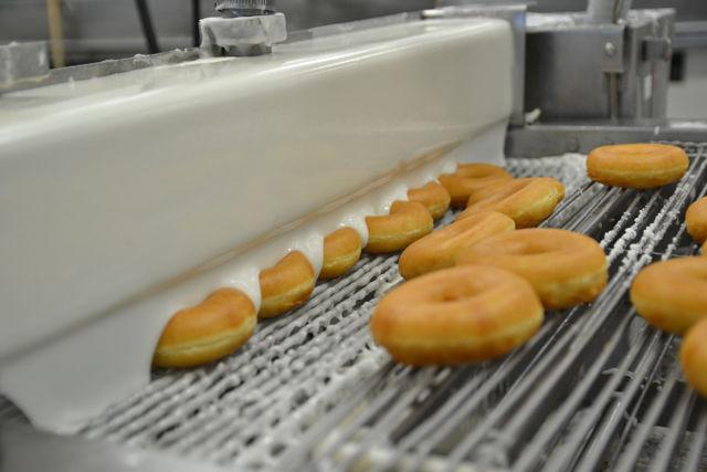 In rows of six, the doughnuts go under the icing machine to be made into the orginal glazed doughnuts. Participants of the Krispy Kreme Challenge will be eating a dozen original glazed doughnuts at the halfway point at the Krispy Kreme store in Downtown Raleigh.