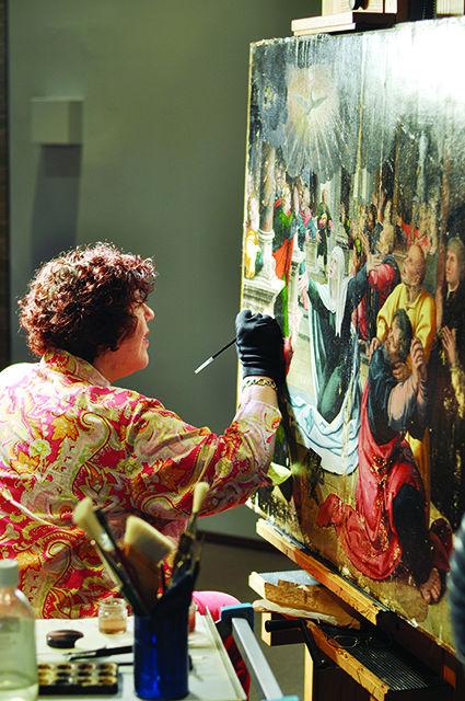 North Carolina Museum of Art painting conservator Noelle Ocon works on restoring a piece as part of Actual State, an exhibition running now through July 10, 2016. On display at Actual State was The Ascension, a finished restoration piece, and The Pentecost, shown, both attributed to a follower of Bernard van Orley circa 1530. Ocon shared that using resins and pigments is safer than the original medium of oil paint because the resin can be removed if the painting needs to be restored again.