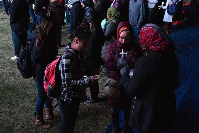 Sapphira Mohammad, a student at Wake Tech, and Hoda Abrahim, a student at NC Central University, attempt to light candles at the end of the memorial Wednesday night. Students from all over the community came to the memorial held on Stafford Commons on Wednesday, Feb 10, 2016.