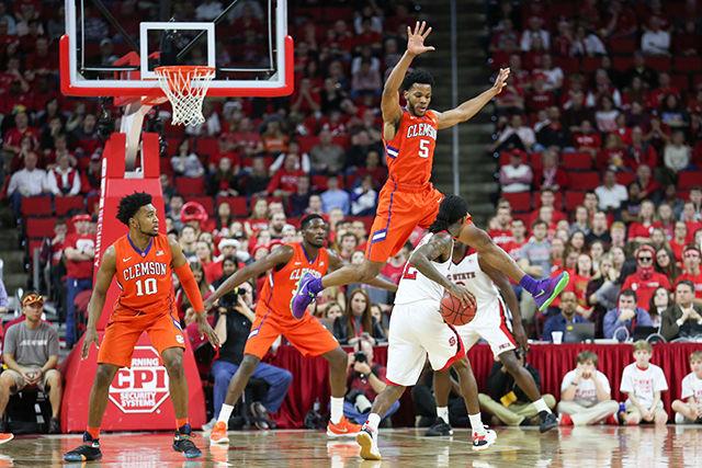 A clemson defender flies into the air while defending 'Cat' Barber during the Clemson vs NC State basketball game at PNC Arena on February 20, 2016.