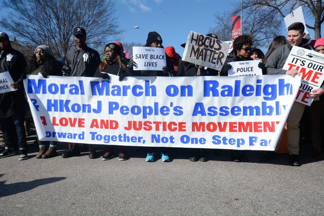 Protesters at the front line of the HKonJ march hold up a sign for the event along with various other signs for different movements on Feb. 13, 2016. The theme of this year's event is to get out the vote and the campaign is being called &#8220;This is our Selma, our time, our vote.&#8221;