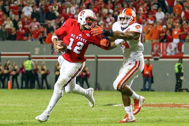 Redshirt senior quarterback Jacoby Brissett stiffarms a defender and looks downfield to attempt a throw against Clemson's defense. Brissett finished the game with three touchdowns and 254 yards on 24-of-41 throwing and one rushing touchdown on eight carries for 34 yards. The Wolfpack fell to the Tigers 56-41 in Carter-Finley Stadium Oct. 31.